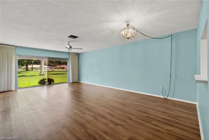 Spare room featuring a textured ceiling, ceiling fan with notable chandelier, and wood-type flooring