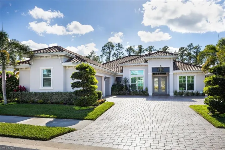 Traditional Florida-style house with french doors, paver stone driveway, stucco siding, an attached garage, and a tile roof