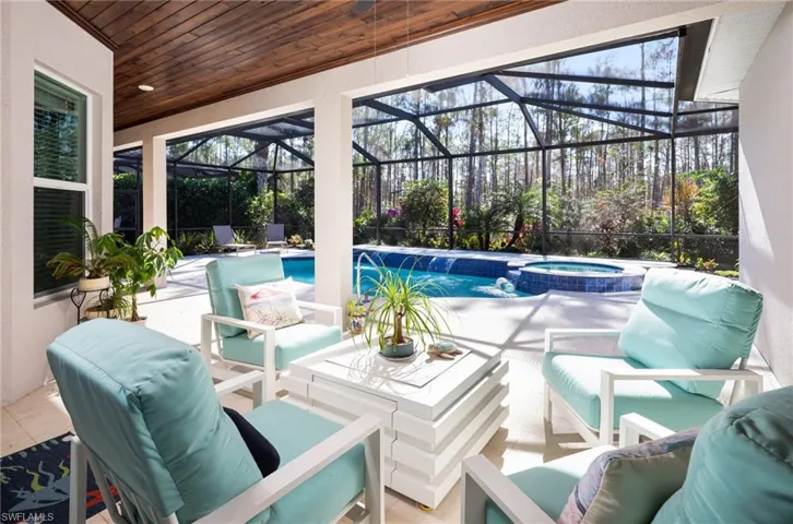View of patio featuring a sunroom, a lanai, a pool with connected hot tub, and an outdoor living space