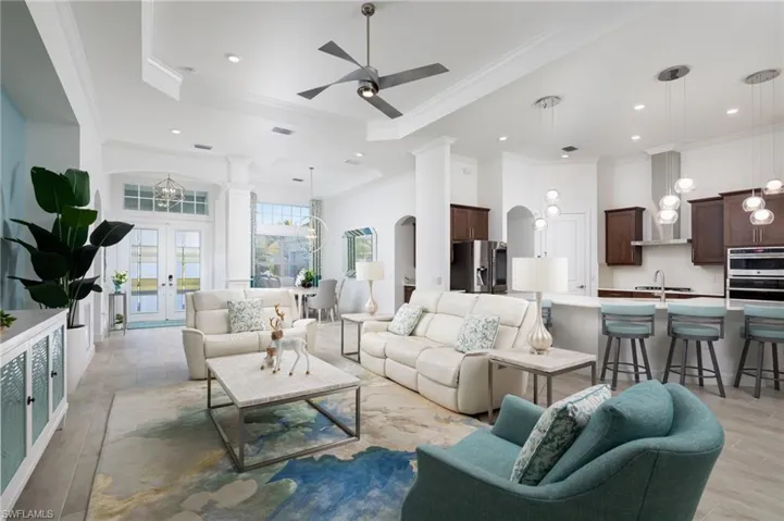 Living area featuring arched walkways, ornamental molding, a chandelier, a ceiling fan, and a towering ceiling