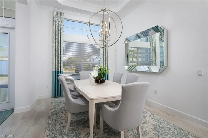 Dining area featuring ornamental molding, a chandelier, wood finish floors, and a raised ceiling