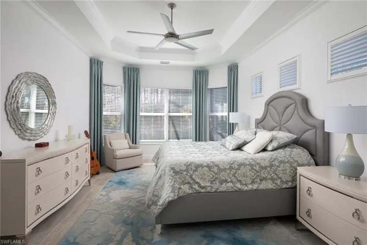 Primary bedroom with ornamental molding, a ceiling fan, a raised ceiling and 2 walk-in closets