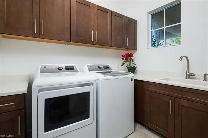 Washroom with cabinet space, washing machine and clothes dryer, and light tile patterned floors