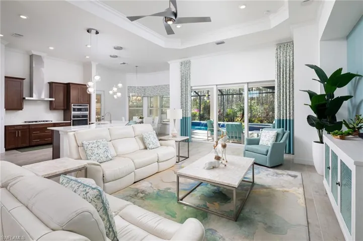 Living room featuring a high ceiling, crown molding, a ceiling fan, recessed lighting, and light wood-type flooring