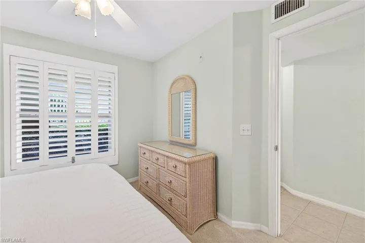 Window with white plantation shutters and a ceiling fan with light fixture