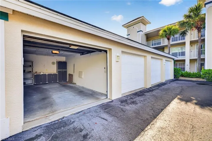 Attached garage with an open bay, concrete flooring, and built-in storage cabinetry