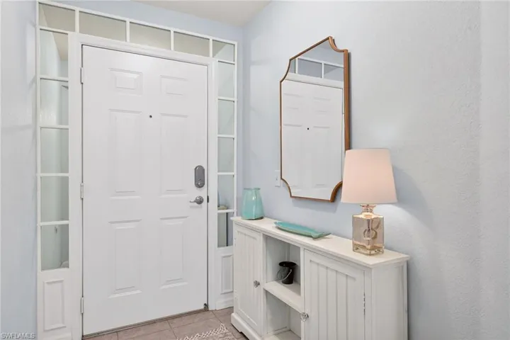 Entryway with a paneled white door, transom window, and sidelight windows