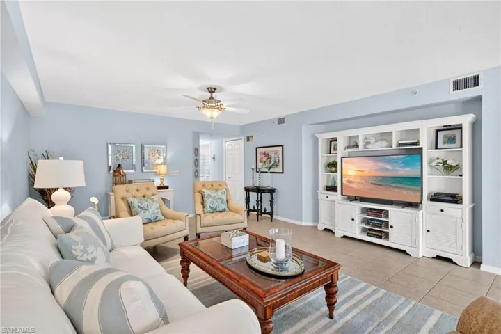 Expansive living area featuring tile flooring, a built-in media center with shelving, a ceiling fan with integrated lighting, and light blue wall tones
