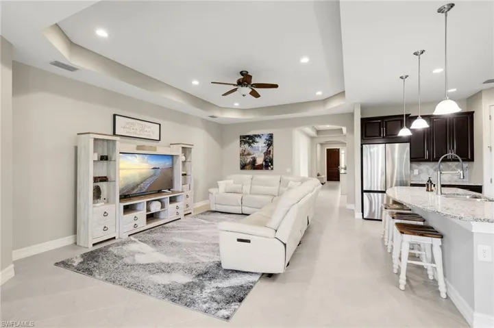 The living room showcases a stunning tray ceiling with a ceiling fan and provides direct access to the large screened lanai.