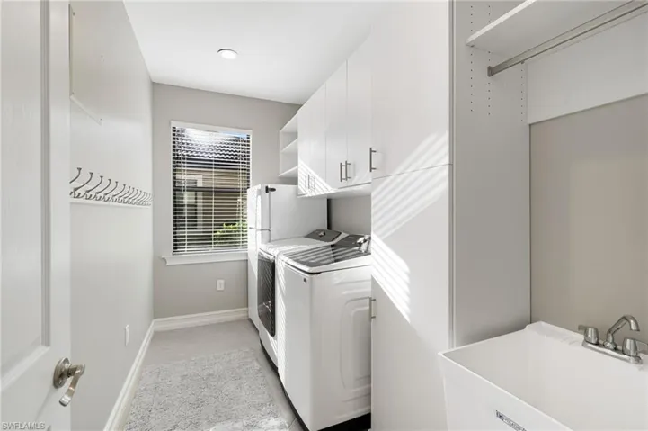 Well-equipped laundry room with brand-new Samsung washer and dryer, abundant overhead storage, a utility sink, and an extra refrigerator.