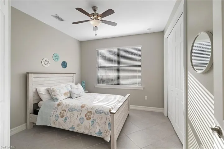 Bedroom two features double doors, tile flooring, a ceiling fan, and ample closet space.