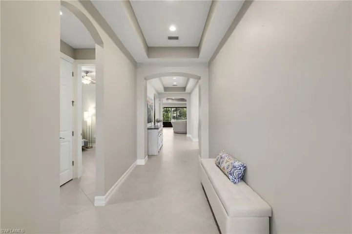The front entry welcomes you into a light-filled home featuring elegant tray ceilings, arched doorways, and tile flooring that extends throughout the living spaces.