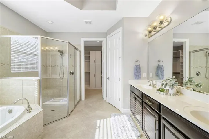 The private ensuite bathroom offers a spa-like experience with a soaking tub, a walk-in tiled shower, dual vanities, and a spacious walk-in closet with custom built-ins.