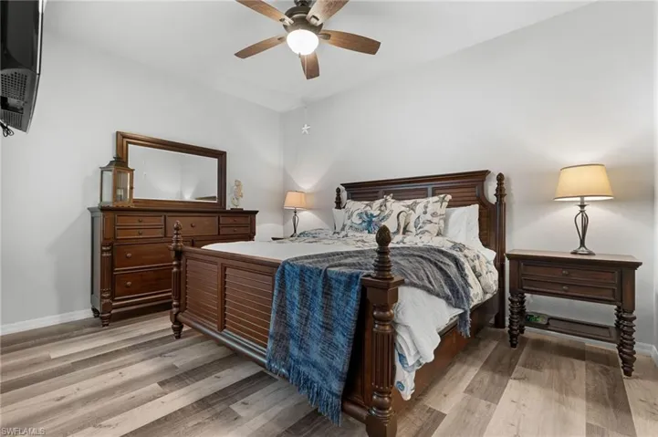 Master bedroom with wood-finish vinyl flooring, ceiling fan with integrated lighting