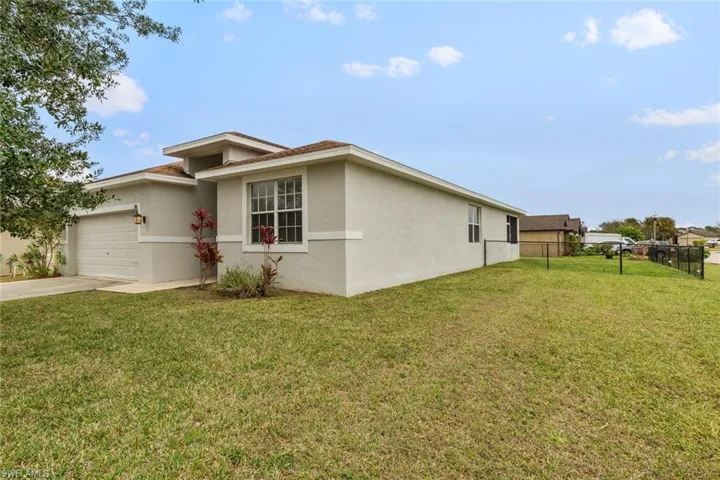 View of side of property with a garage, stucco siding, and driveway