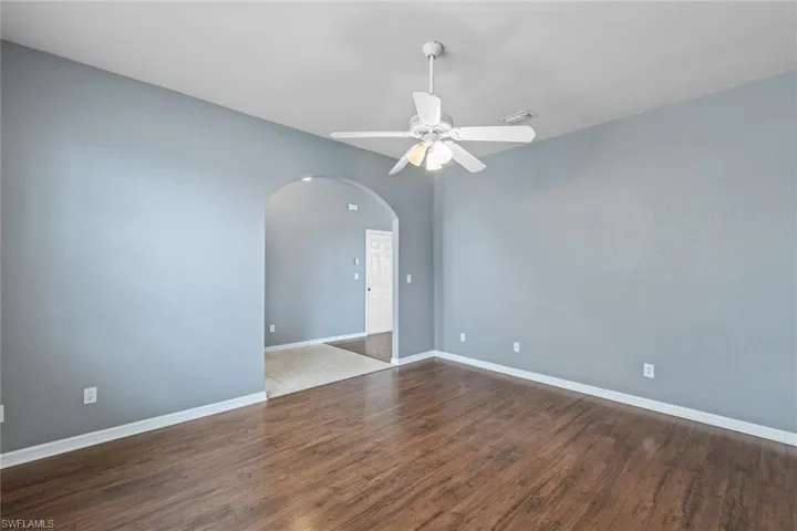 Spare room featuring a ceiling fan, dark wood-type flooring, and arched walkways