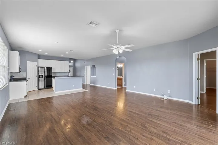 Unfurnished living room featuring arched walkways, ceiling fan, dark wood-style flooring, and recessed lighting