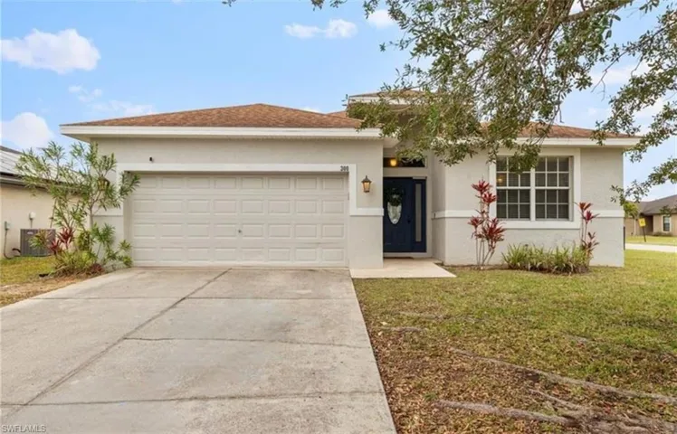 Ranch-style home with stucco siding, a front yard, an attached garage, and concrete driveway