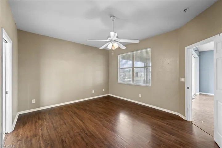 Empty room with dark wood-type flooring and a ceiling fan
