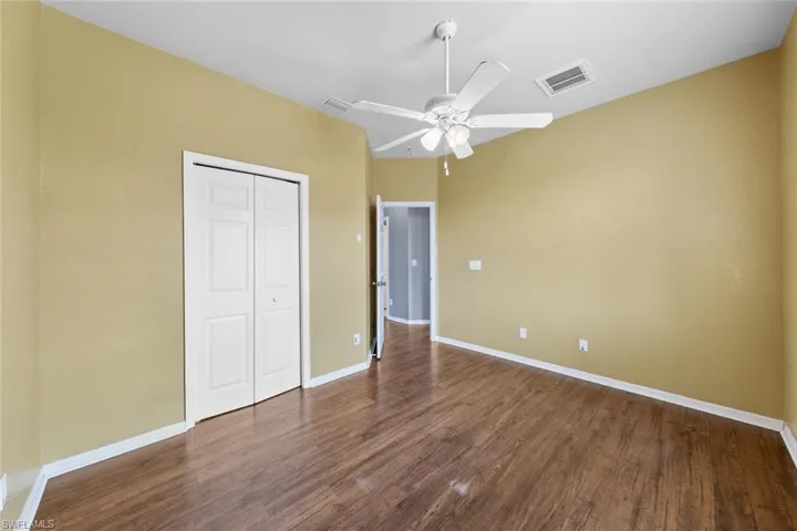 Unfurnished bedroom featuring a closet, dark wood-style floors, and a ceiling fan