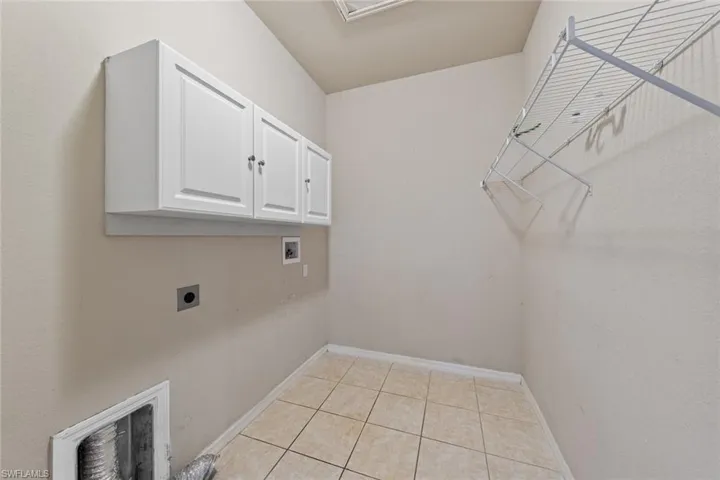 Laundry area featuring electric dryer hookup, washer hookup, cabinet space, and light tile patterned floors