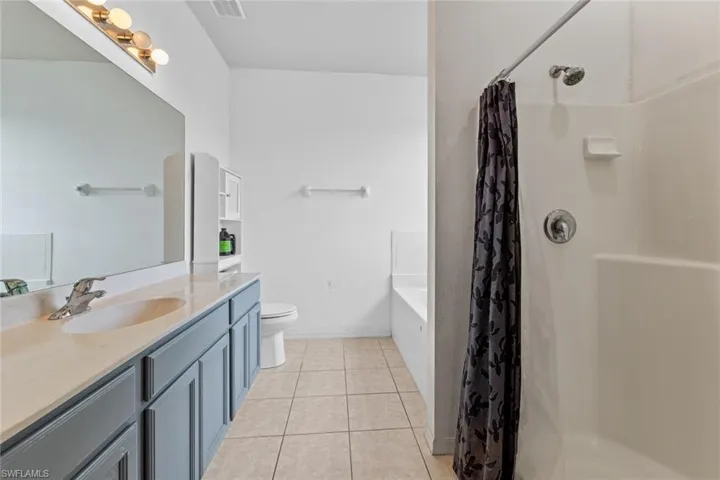 Bathroom with vanity, light tile patterned floors, a shower stall, and a bath