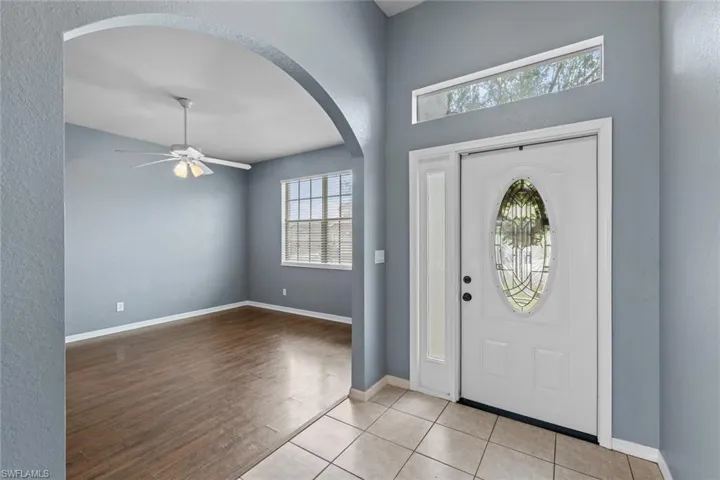Entrance foyer with ceiling fan, a textured wall, light tile patterned floors, and arched walkways