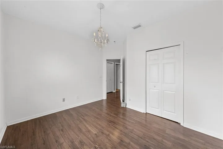 Unfurnished bedroom featuring suspended lighting, dark wood finished floors, and a closet