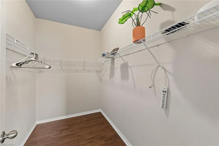 Walk in closet with dark wood finished floors