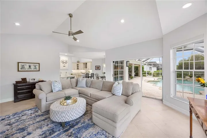 Living area featuring vaulted ceiling, light tile patterned floors, ceiling fan, and recessed lighting