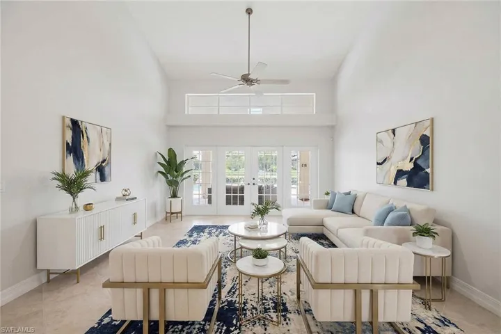 Tiled living room with a ceiling fan, french doors, and a high ceiling