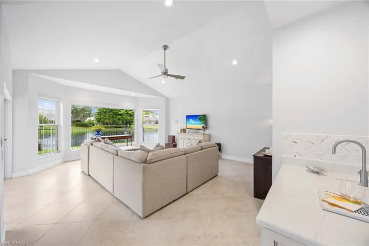 Living room featuring vaulted ceiling, light tile patterned floors, ceiling fan, and recessed lighting