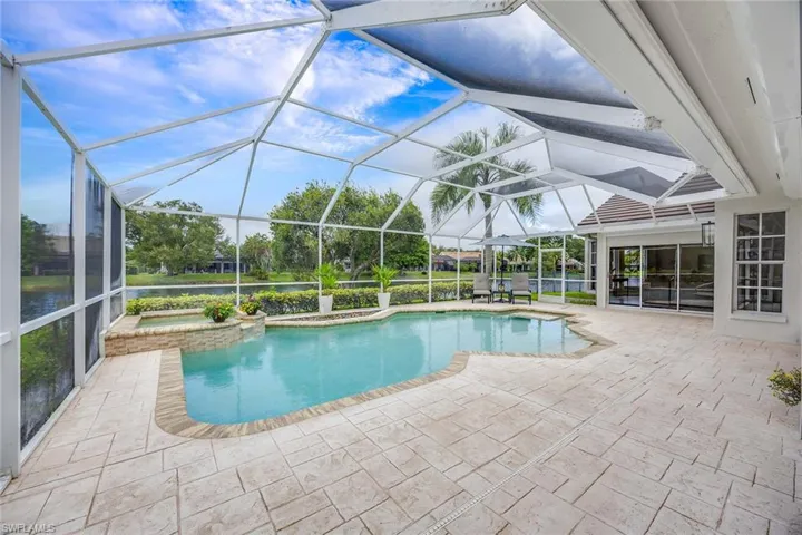View of pool with a sunroom, a patio, a pool with connected hot tub, and glass enclosure