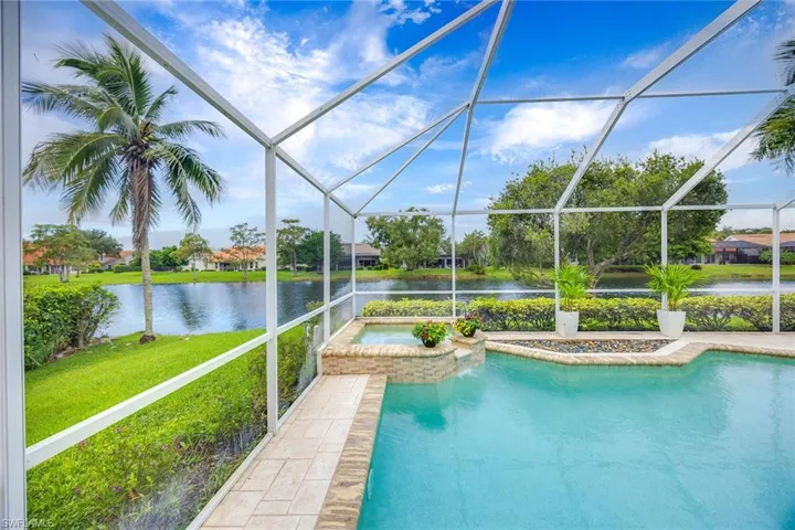 View of swimming pool with a sunroom, glass enclosure, a water view, a yard, and a pool with connected hot tub