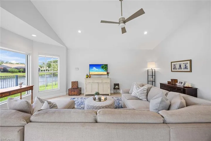 Carpeted living room featuring a ceiling fan, recessed lighting, and high vaulted ceiling