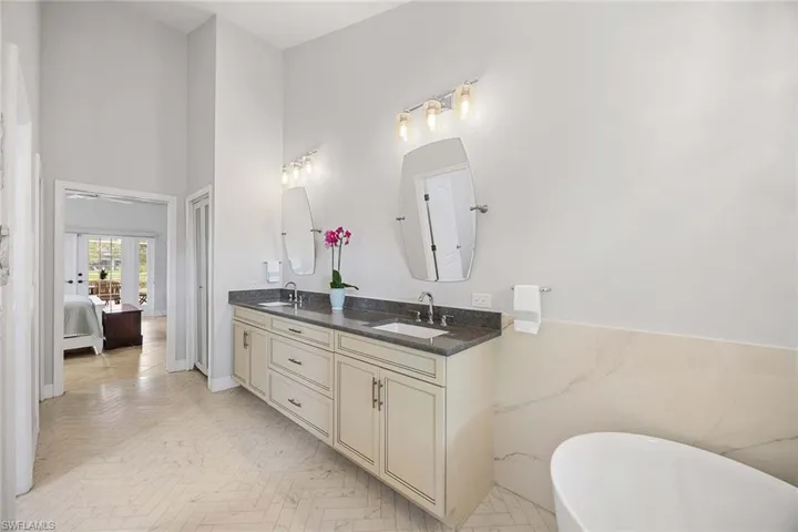 Full bathroom with double vanity, a high ceiling, a soaking tub, and ensuite bath