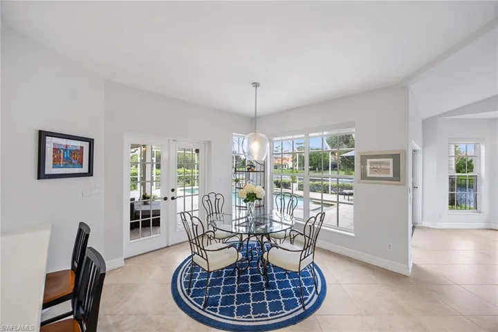 Dining area with french doors, light tile patterned floors, lofted ceiling, and a chandelier
