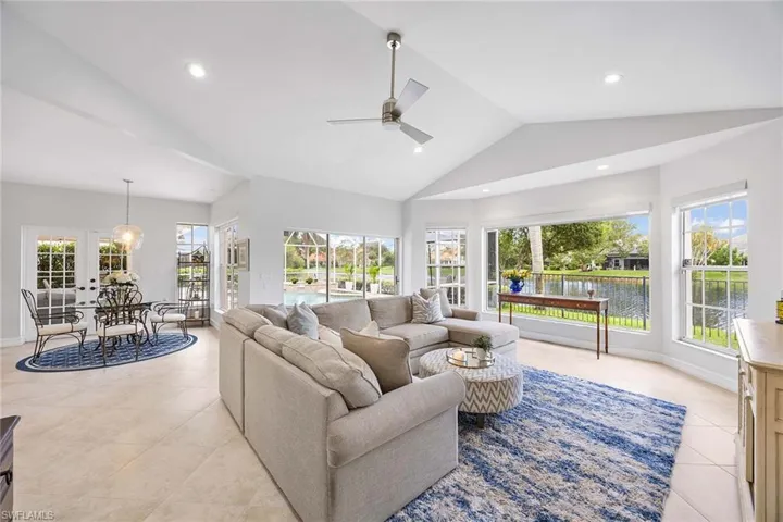 Living room featuring vaulted ceiling, plenty of natural light, a ceiling fan, light tile patterned flooring, and french doors
