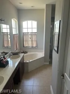 Bathroom featuring double vanity, a bath, and light tile patterned flooring