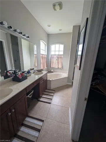 Bathroom with double vanity, a bath, light tile patterned floors, a shower stall, and a walk in closet