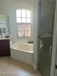 Full bath with vanity, a stall shower, a bath, and light tile patterned floors