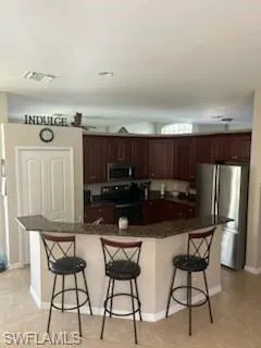 Kitchen featuring a kitchen breakfast bar, a large island, appliances with stainless steel finishes, and light tile patterned floors