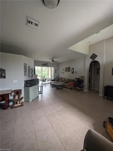 Living area with ceiling fan, light tile patterned floors, and arched walkways