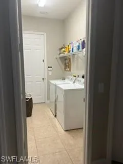 Laundry room with light tile patterned floors and washing machine and clothes dryer