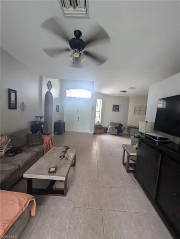 Living room featuring light tile patterned floors, arched walkways, and ceiling fan
