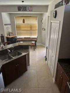 Kitchen featuring dark stone counters, light tile patterned floors, and dark brown cabinetry