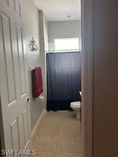 Full bathroom featuring light tile patterned floors and curtained shower