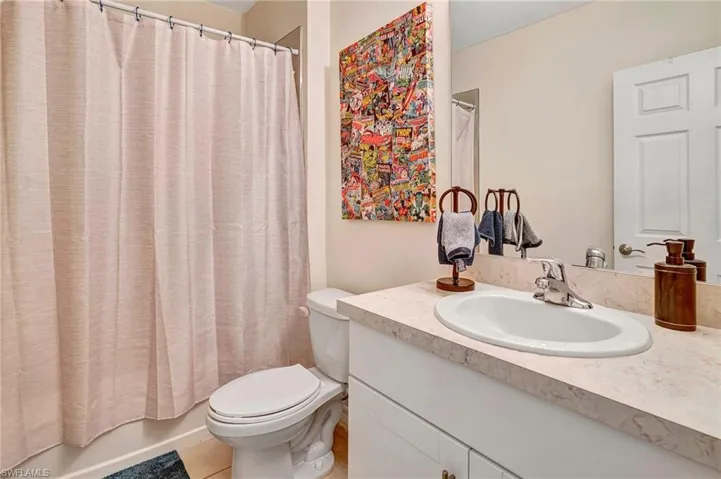 Full bathroom with tile floors, shower / tub combo with curtain, toilet, and large vanity