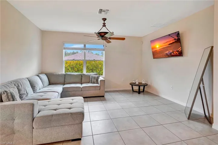 Living room with ceiling fan and light tile floors