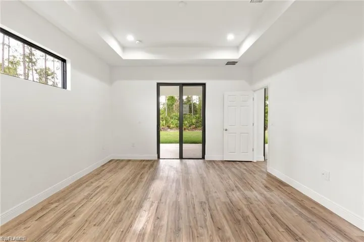 Empty room with light hardwood / wood-style floors and a raised ceiling